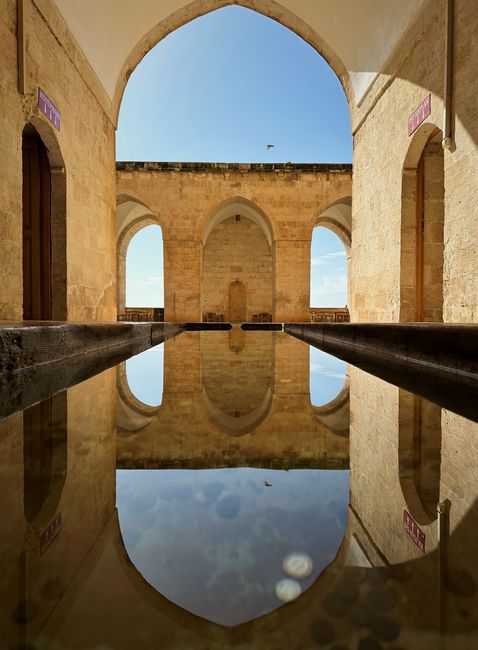 Majestic archways and water reflection in historic Mardin, Türkiye.