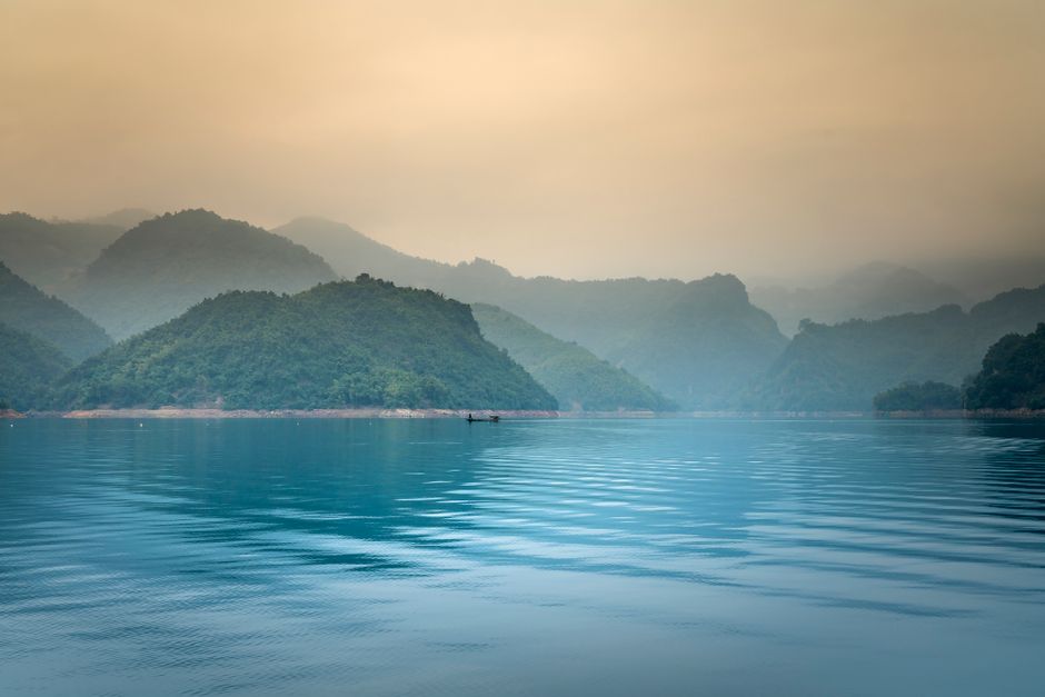Tranquil scene of a misty lake with mountains reflecting in the calm water.